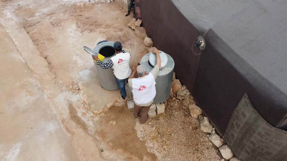 Aerial photo of 2 MSF Team members setting up water collection tanks.