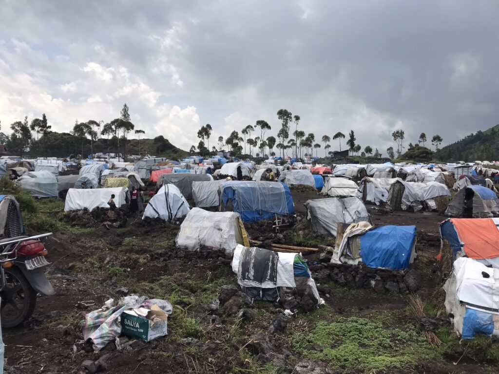 Temporary shelters made mostly of wooden poles, and plastic sheeting, secured by strings in Democratic Republic of Congo.